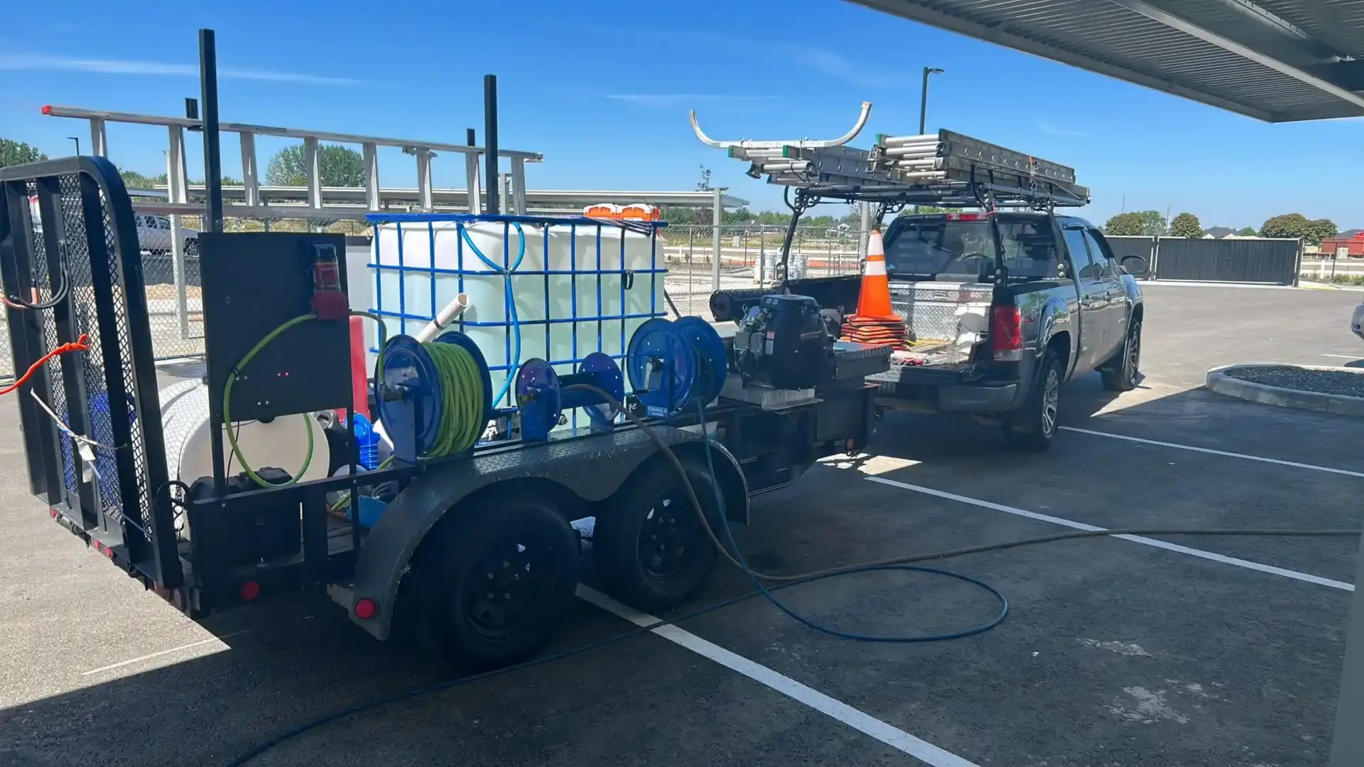 Gem Pro's wash trailer, carrying a water tank, hose reels and pump, hitched to the crew truck at a commercial property.