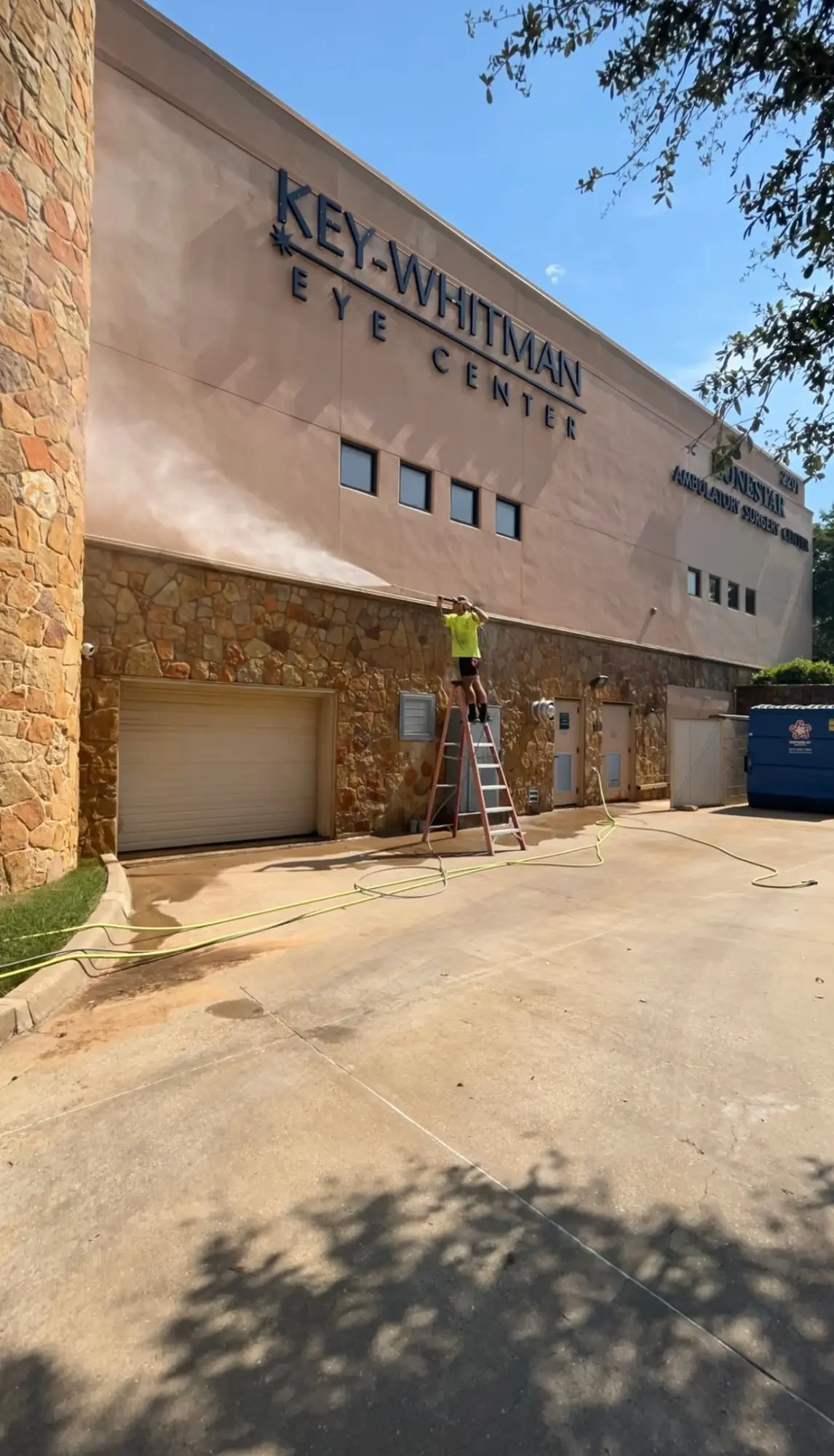 Gem Pro technician soft washing the upper facade of a commercial building